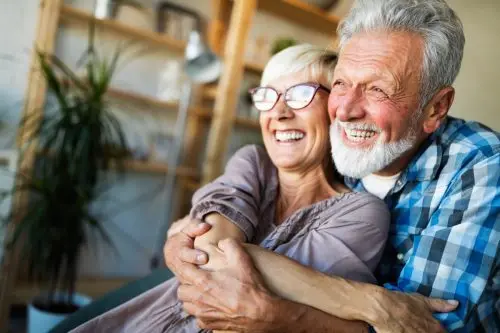 Mature husband and wife hugging and smiling at home