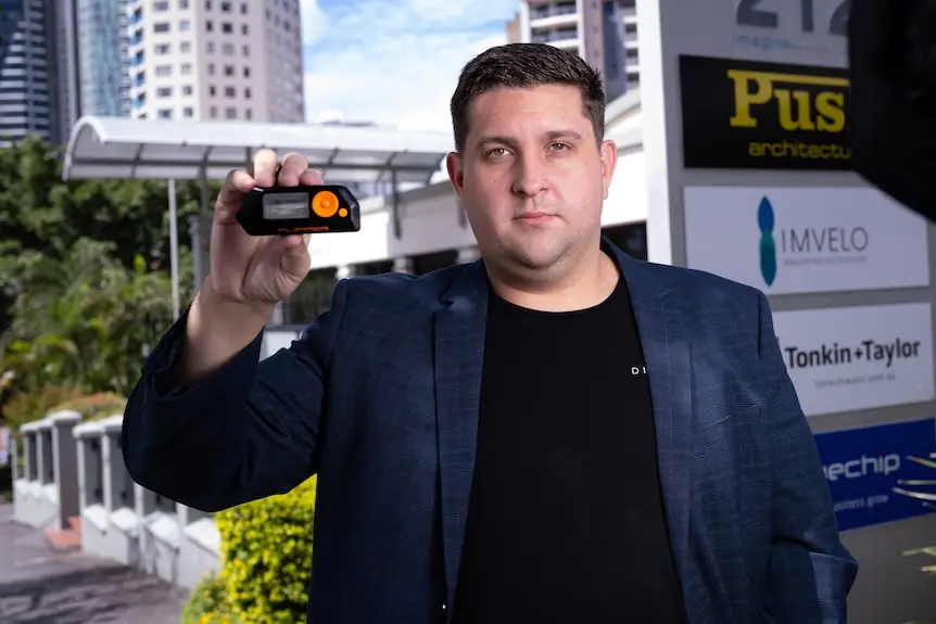 A man holds up a small plastic gadget