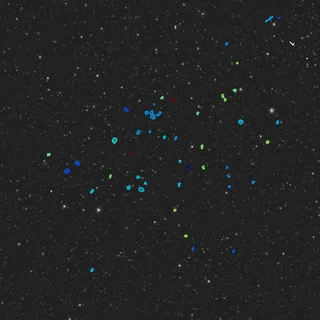 a view of a patch of space, with dozens of distant newfound galaxies circled in blue and green.