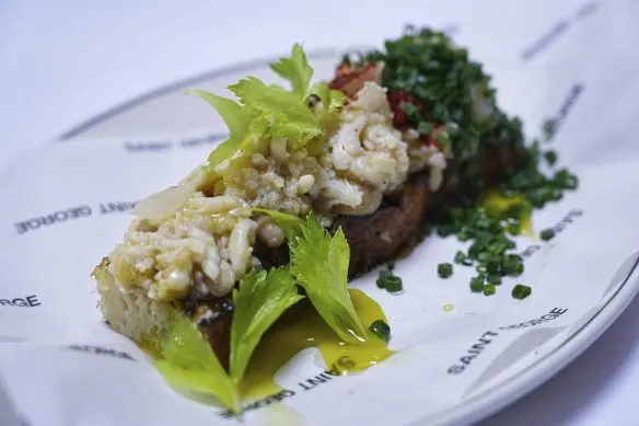 Lemon brown butter-dressed spanner crab on toast, topped with fresh celery leaves.