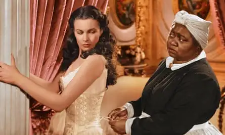 Hattie McDaniel, standing behind Vivien Leigh, pulls at her corset ties in Gone with the Wind