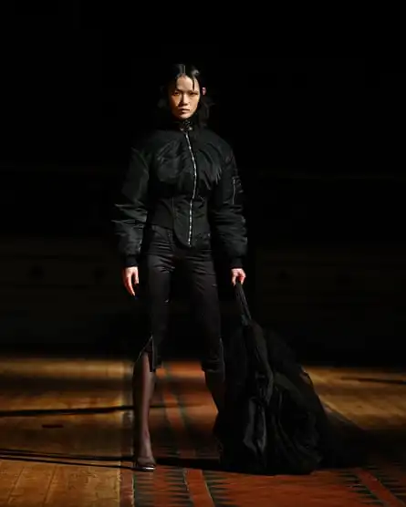 A model wearing a black outfit including a corset-style bomber jacket