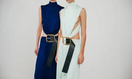 Two models wearing dresses with giant belt buckles.