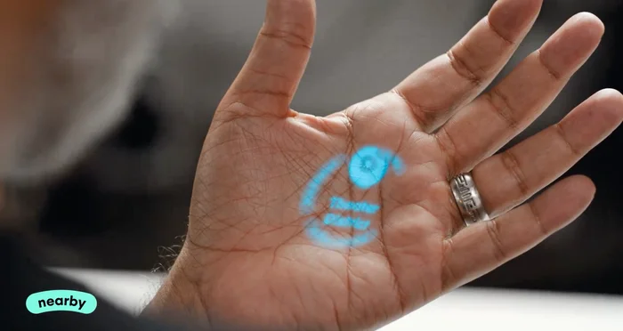 Humane's AI pin projects a blue image onto someone's hand during a demonstration.