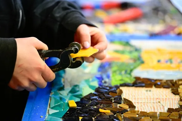 Tara Performing Arts freshman Sophia Love cuts glass pieces for a panel in the mosaic in Boulder on Monday. (Matthew Jonas/Staff Photographer)