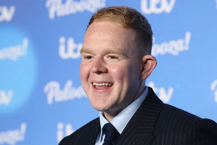 Colson Smith smiling in front of a blurred light blue background