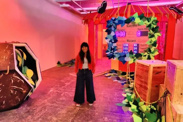 Artist Riso Puno on the floor of her Whac-a-Mole game, in her installation 