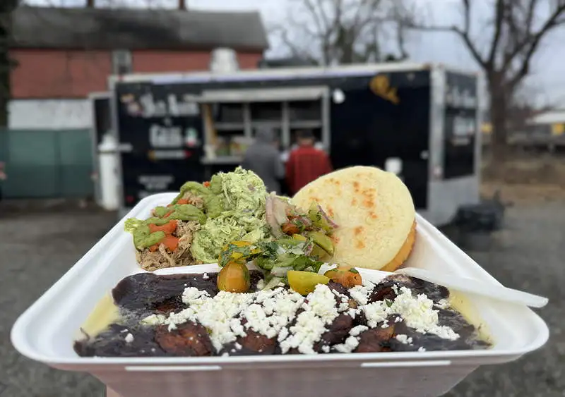 A takeout container of food with a food truck in the background