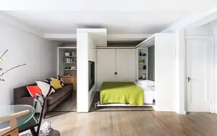 A small apartment with bed, lounge and dining area all visible
