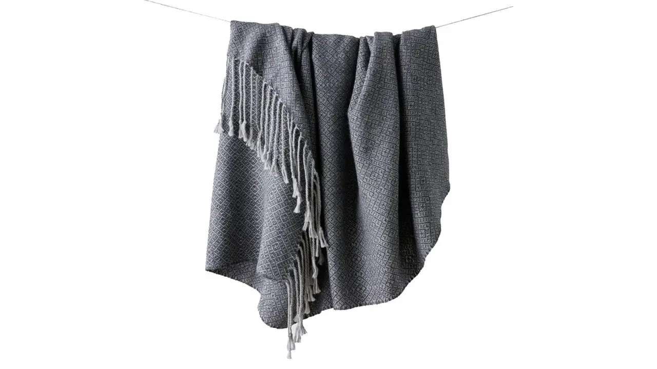 The Citizenry Lirio Alpaca Throw hanging on a line against a white background.