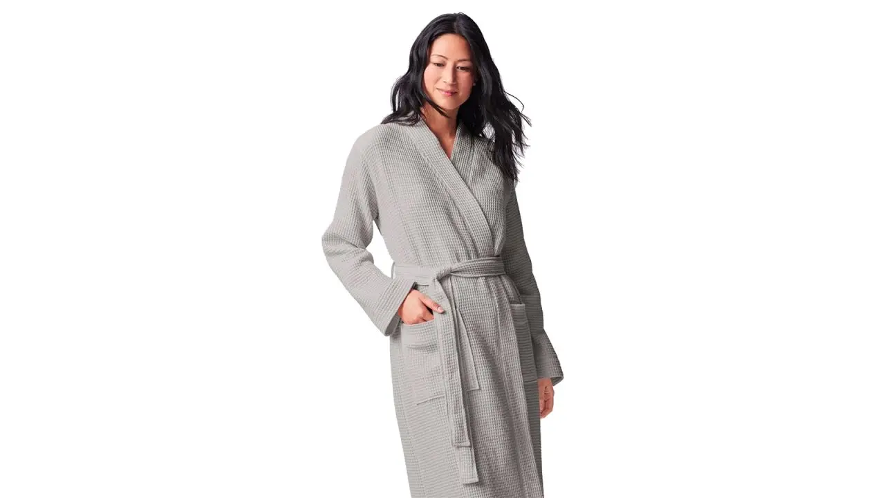 A woman wearing a grey Coyuchi Unisex Organic Waffle Robe on a white background.