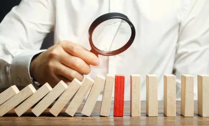 Businessman looks on collapse domino effect. Stress resistance business. Financial stability. Recovery business. Evaluation of cash risks. Creating a strategy. Management and planning. Decision making