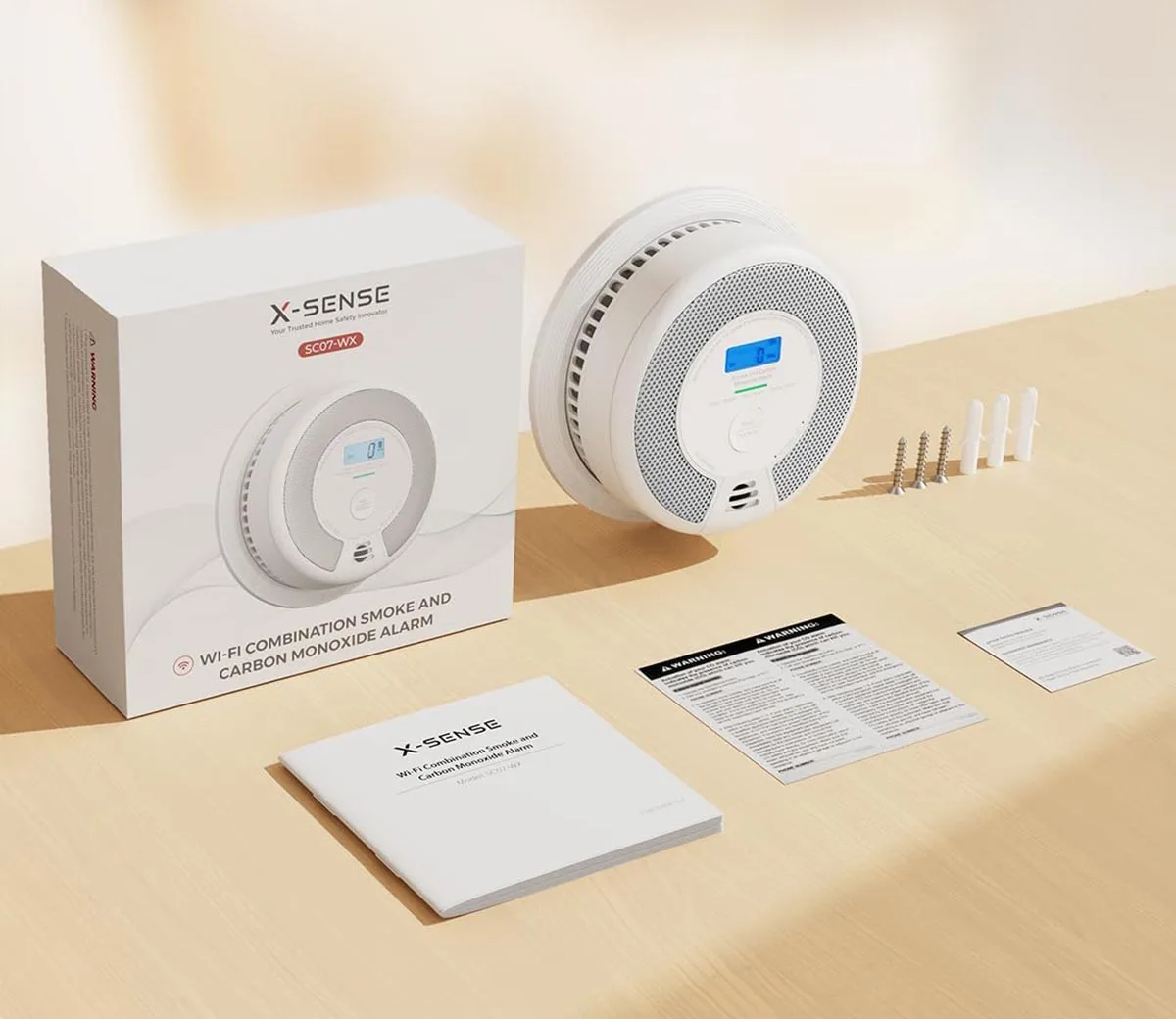 A close up of an X-sense smoke alarm and its components and box laid out on a table. 