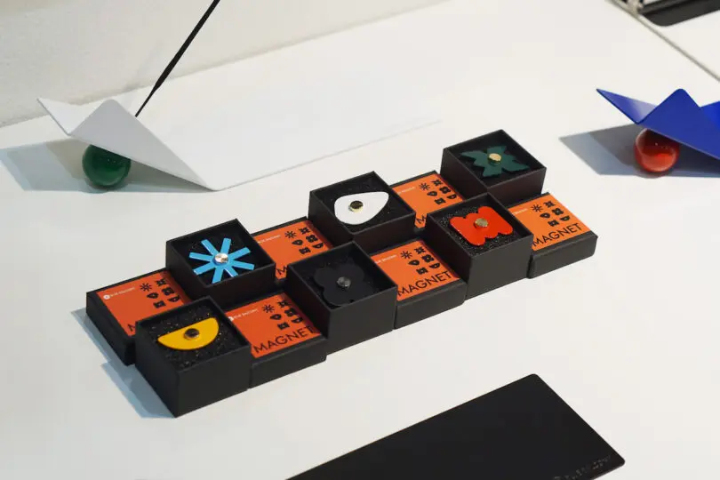 assorted magnets resembling flowers and different shapes in their boxes on a white table