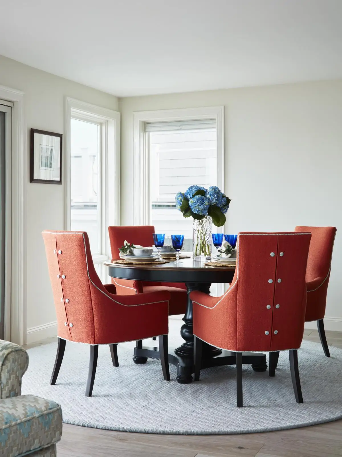 Orange dining chairs in a tailored style surround a circular dining room table.