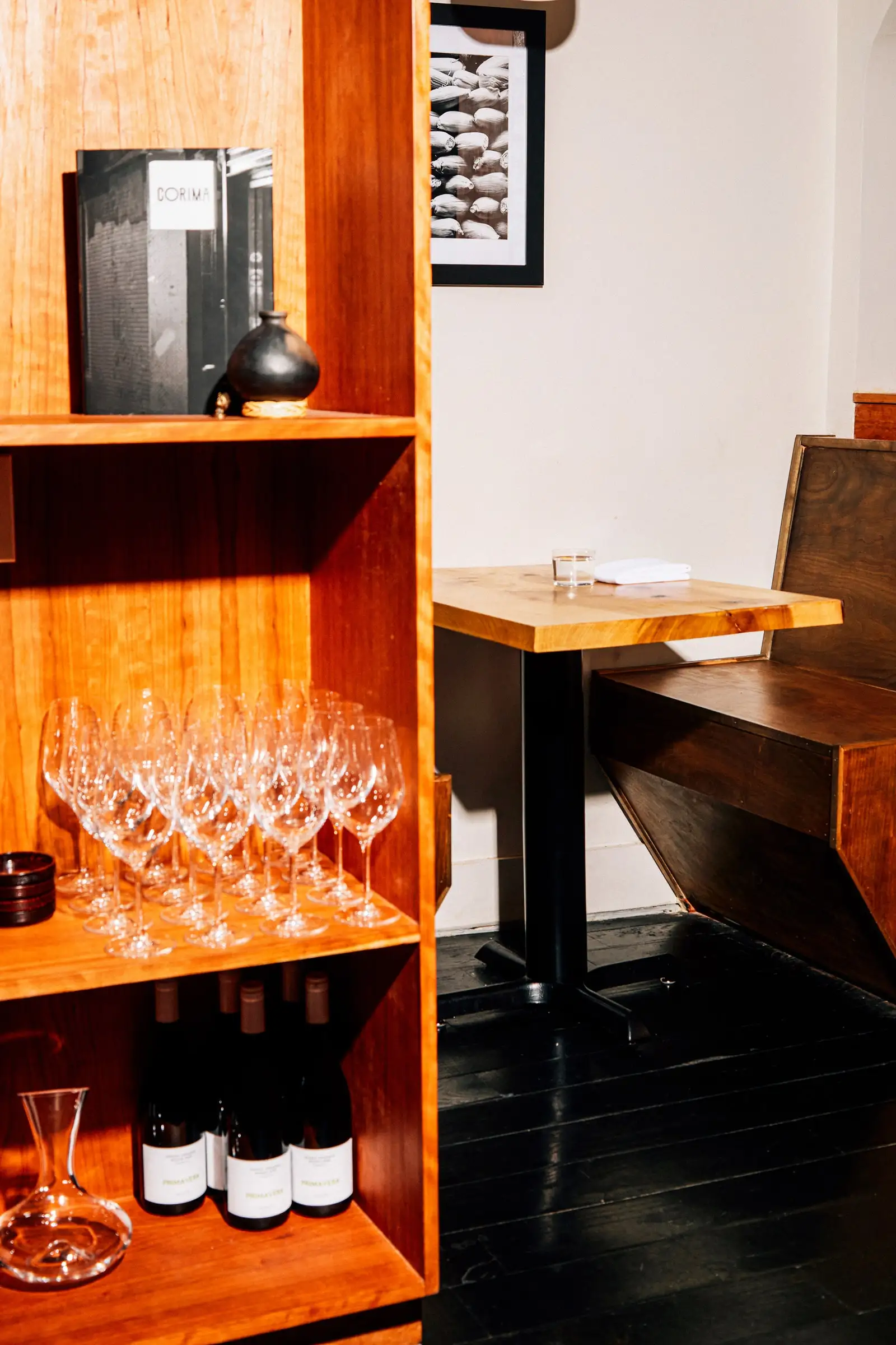 Shelves filled with wine and wine glasses next to a small table.