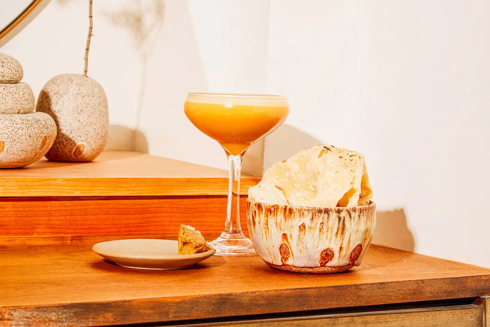 An orange cocktail in a coupe glass.