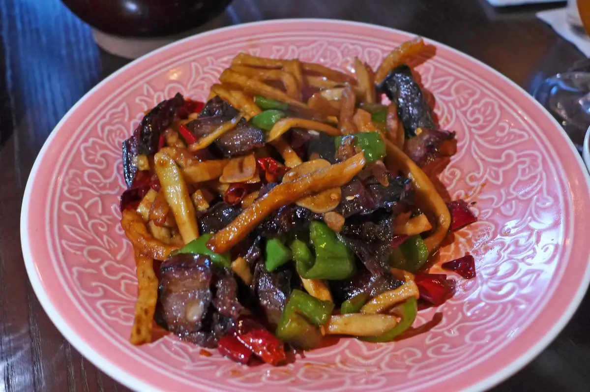 A pink plate with swatches of beef and strips of dried white radish.