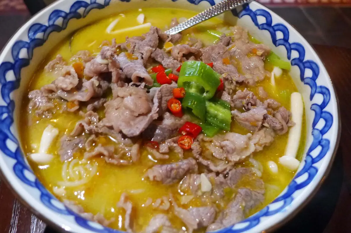 A yellowish broth with curls of beef and red and green chiles.