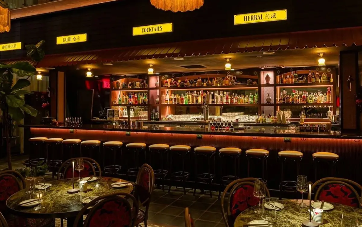 A bar with 20 or so stools, very dark, with lit signs above for various forms of alcohol.