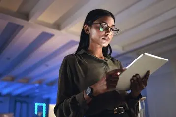 Tableta, diseñadora y mujer seria investigan en la oficina de inicio de negocios por la noche en la fecha límite. Tecnología, profesional creativo o empresario indio leyendo información, correo electrónico o aplicación en neón empresa - Fotografía de stoc