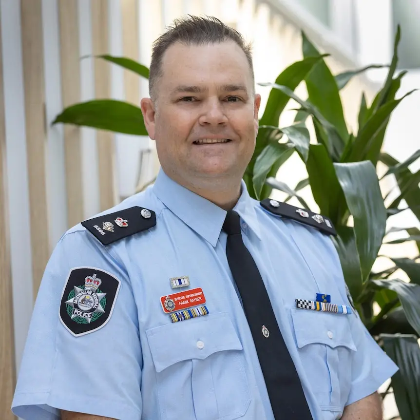 A male police officer in his uniform with short cropped hair.