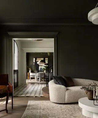 A green living room with a curved boucle sofa and a vintage patterned rug