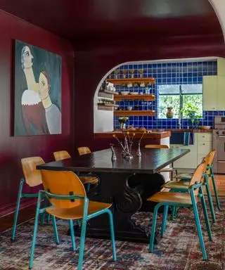 dark red dining room with wooden chairs and artwork