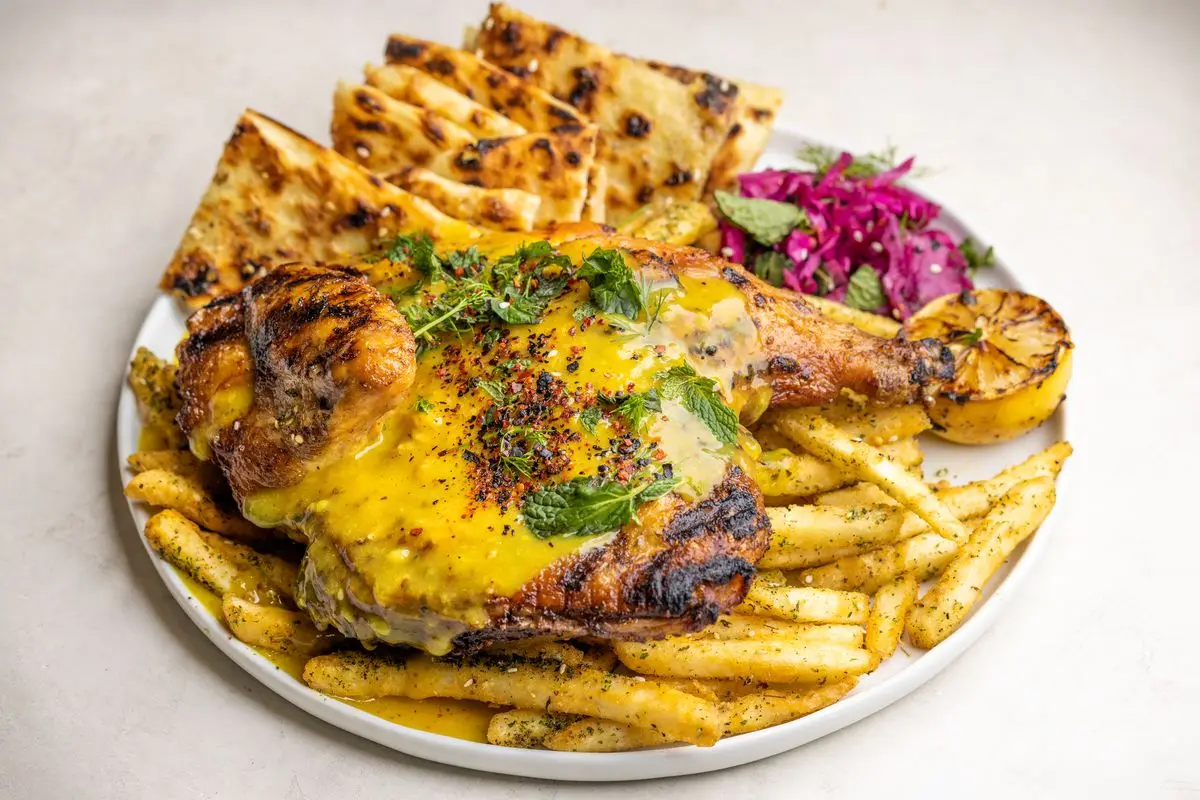 Marinated chicken over fries with flatbread and cabbage at Limone in Torrance, California.