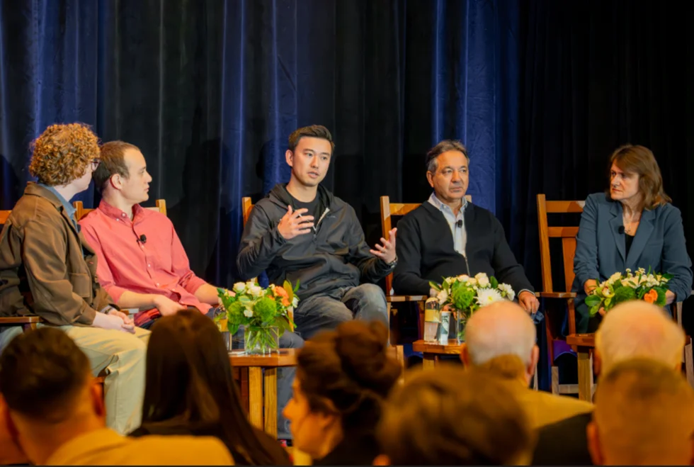 A candid photo of a moderator and four panelists sitting on stage for the AI in drug discovery discussion.