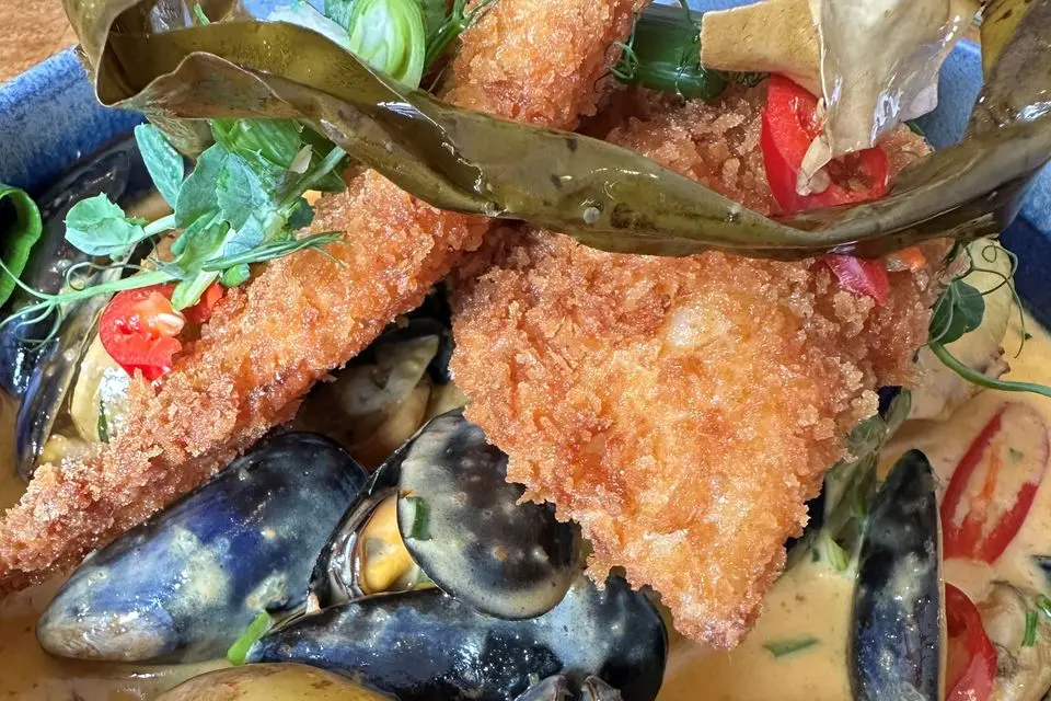 Thai red curry hotpot with breadcrumbed haddock fillets, mussels, new potatoes and scallions, from the menu at Twilight Coffee and Bunkhouse