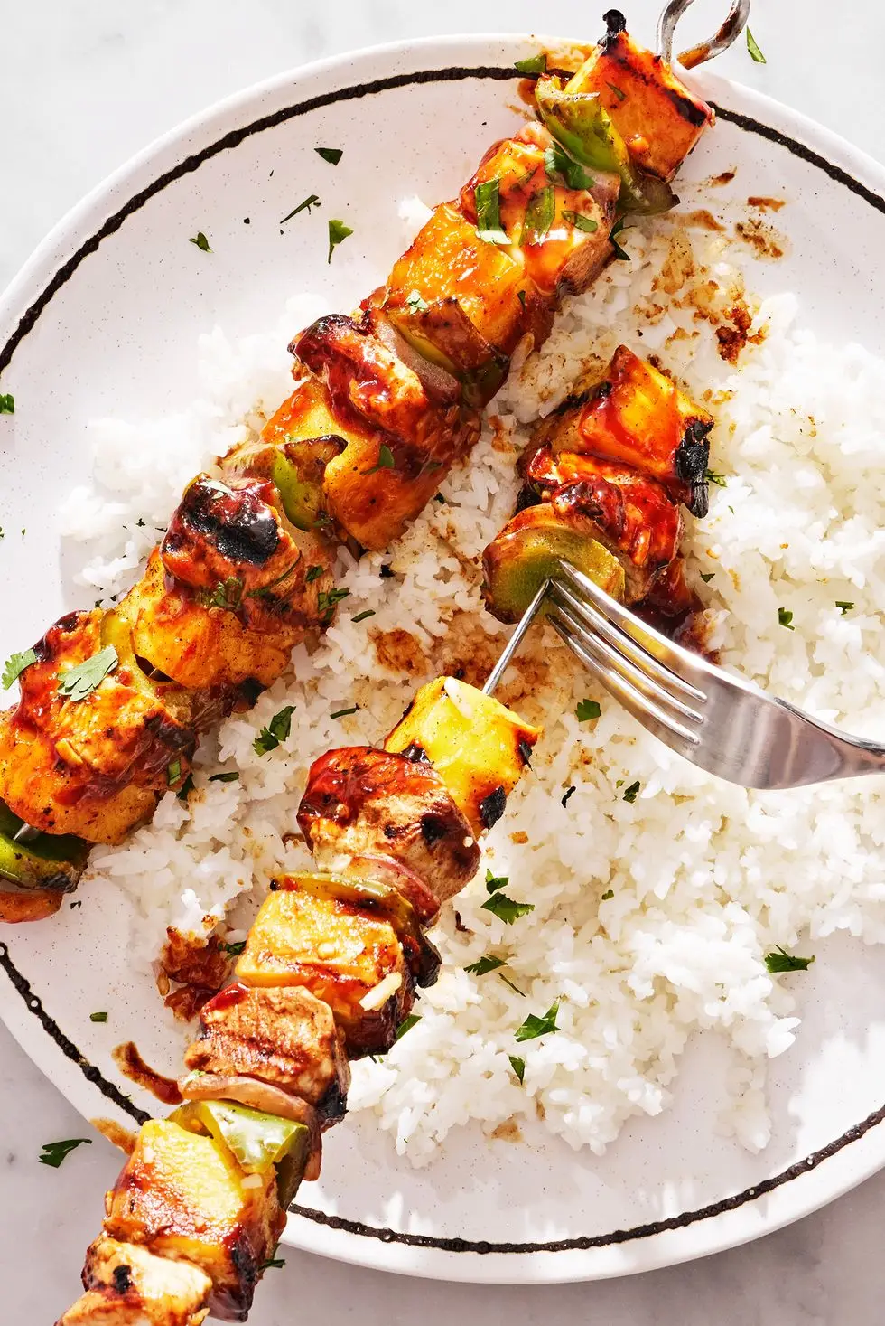 chicken, pineapple, and peppers on a skewer basted with teriyaki