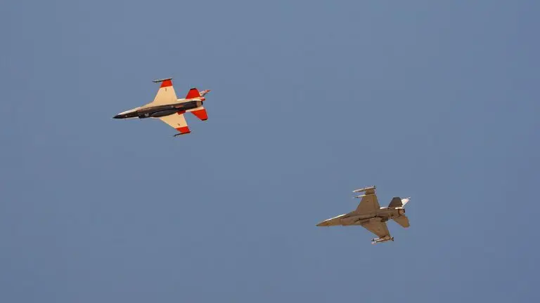 AI-enabled Air Force F-16 fighter jet, left, flies next to an adversary F-16