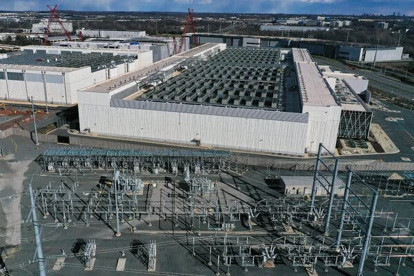 An aerial view of a large data center complex next to a power substation.