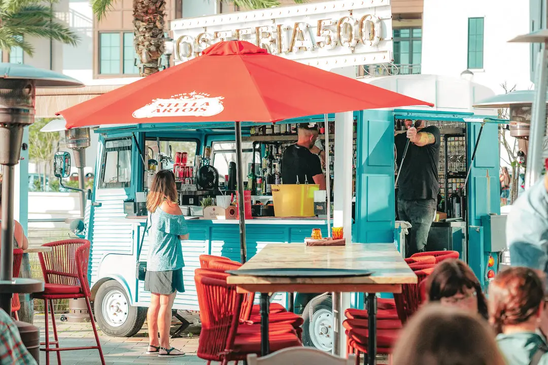 A vintage blue bus on the outdoor patio provides guests with quick access to assorted beverages.