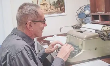 Aira working on a typewriter at a desk in a display at the Museo Barrio de Flores. 