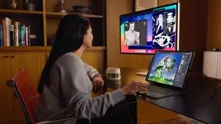 A person sitting at a desk working on an iPad and monitor