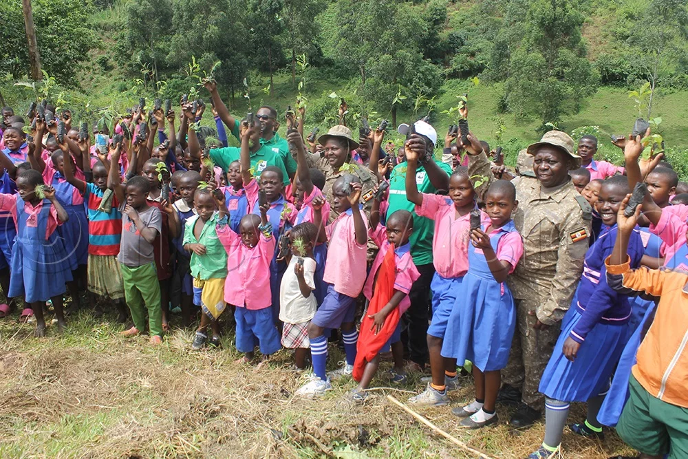 Learners of Kinyampanika Primary School with the staff of UWA pausing with their trees up as a sign of commitment to take care of planted trees. (Photo by Samuel Amanyire) 