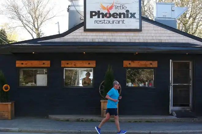 A man runs past the Little Phoenix Restaurant on Acushnet Avenue in New Bedford. Through the window, Audrey Garrison can be seen preparing breakfast for a customer.