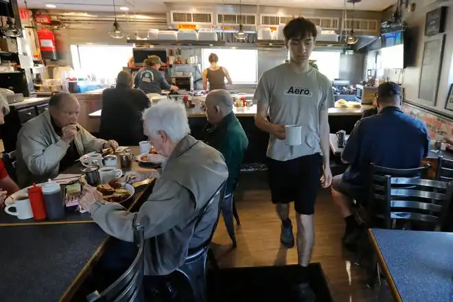 Matthew Carusi brings a cup of coffee to a customer during breakfast at the Little Phoenix Restaurant on Acushnet Avenue in New Bedford.