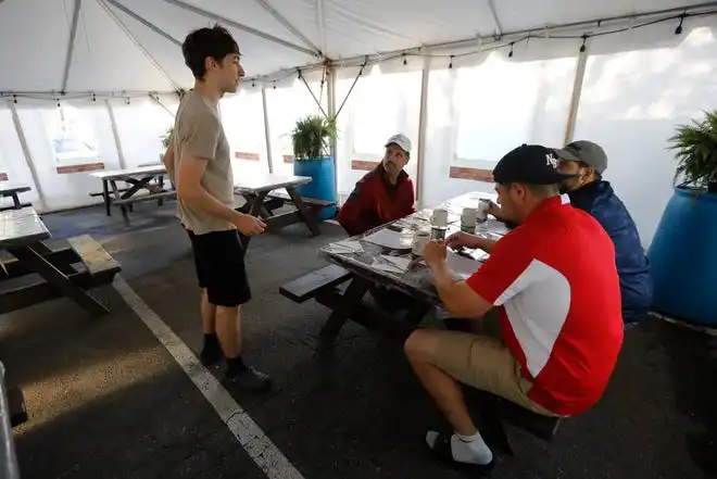 Matthew Carusi takes the breakfast order of patrons sitting inside the new outdoor tent at the Little Phoenix Restaurant on Acushnet Avenue in New Bedford.