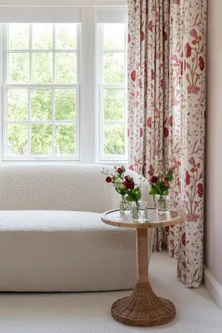 A white boucle couch in a well-lit living room with floral curtains