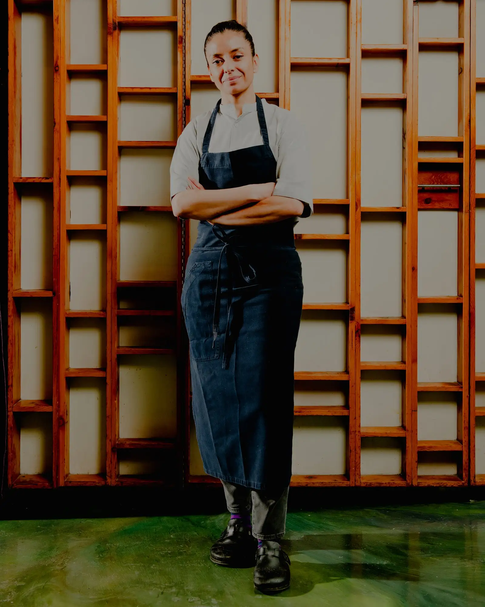 A portrait of Victoria Blamey standing in a chefs apron with arms folded.