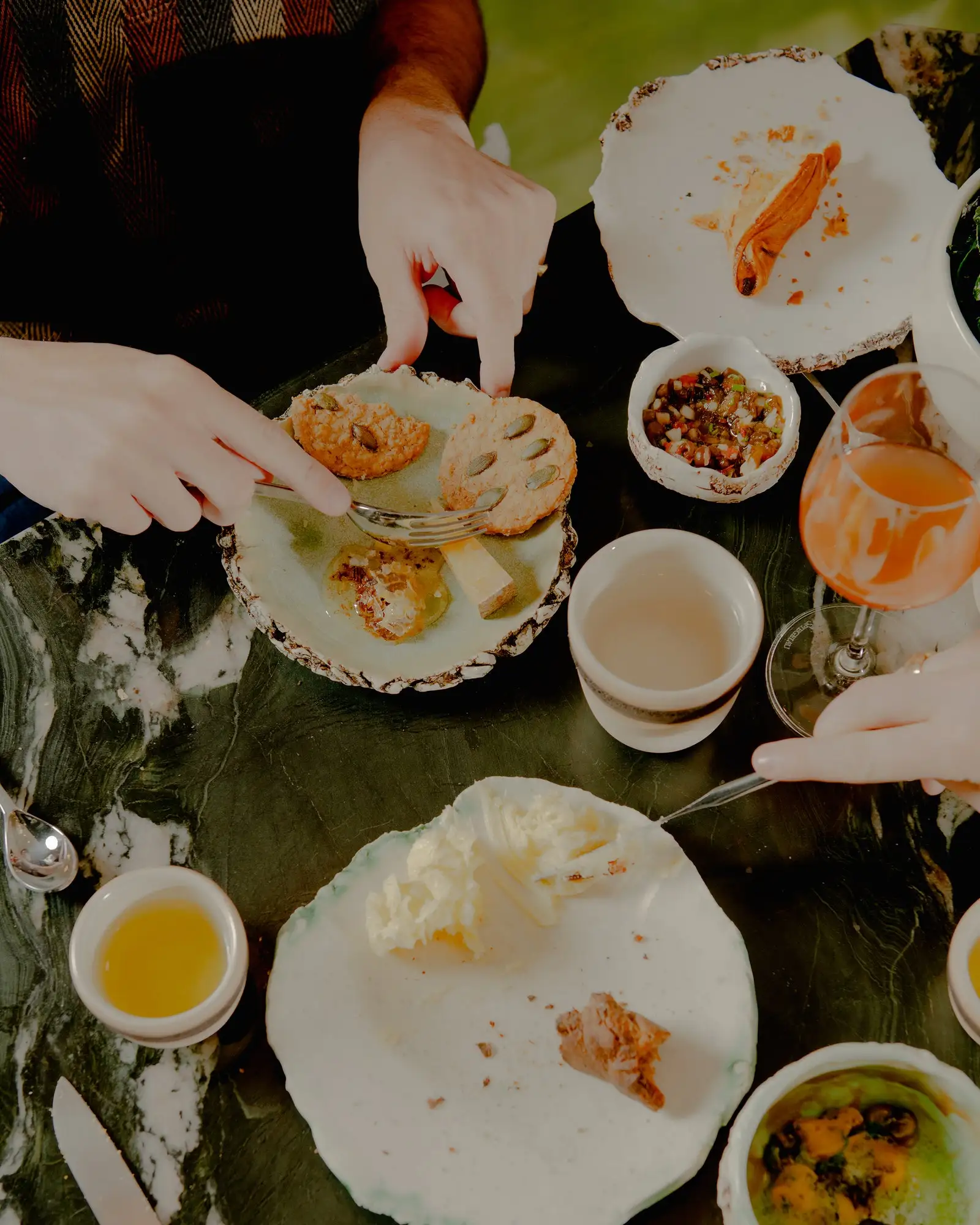 Diners eating a cheese plate accompanied by crackers and honey.