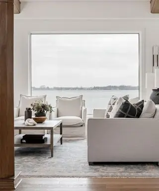 A white and blue living room with a large window view of a lake