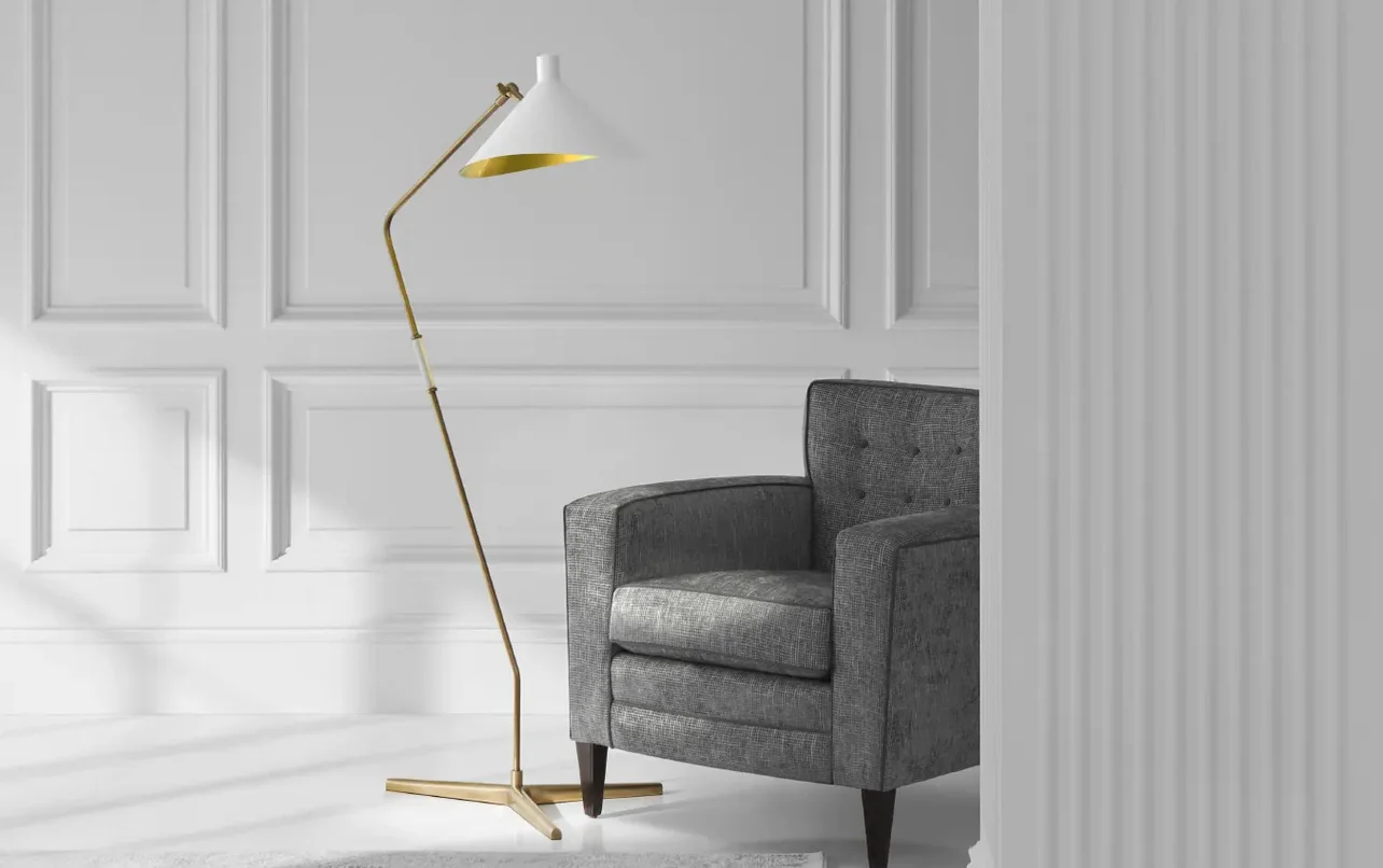 A tall lamp with gold hardware next to a gray chair