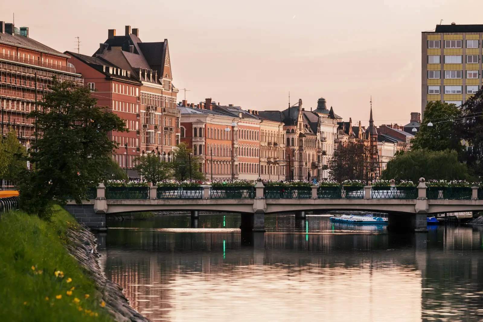 A city skyline by a canal at dusk.