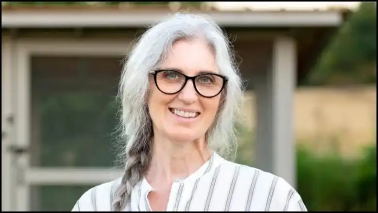 A grey-haired woman looks at the camera.