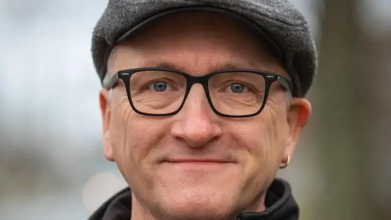 A man wearing a grey hat and black glasses.