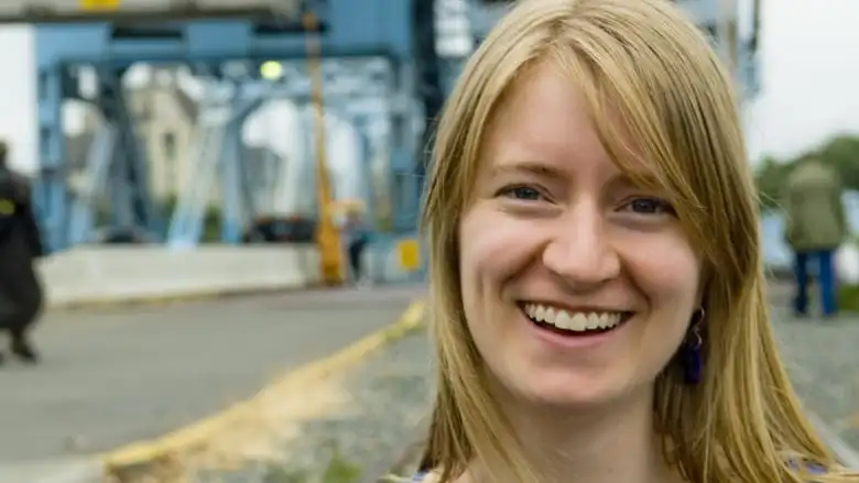 A blonde woman with curtain bangs smiling. 